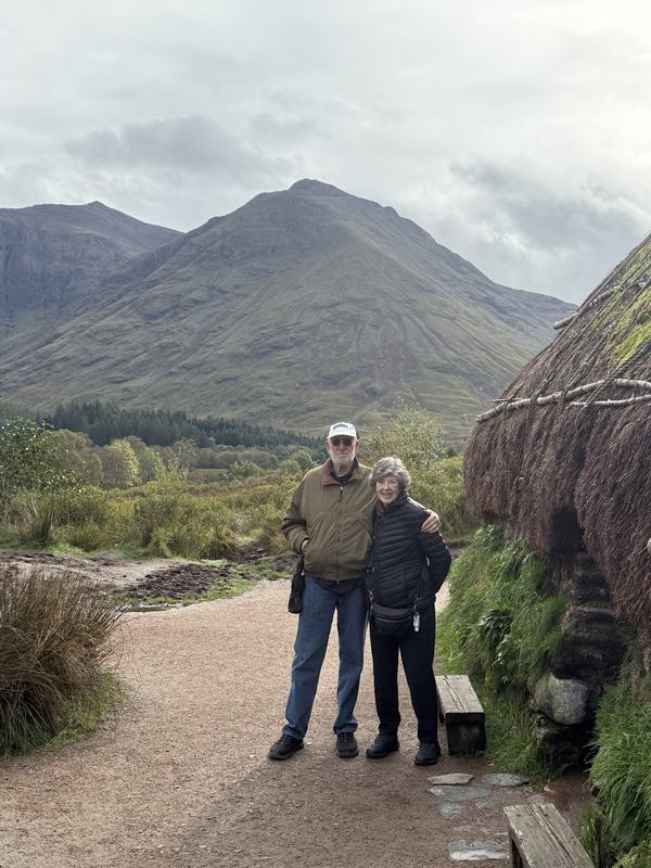 Guests beside the turf house at Glencoe with the mountains behind