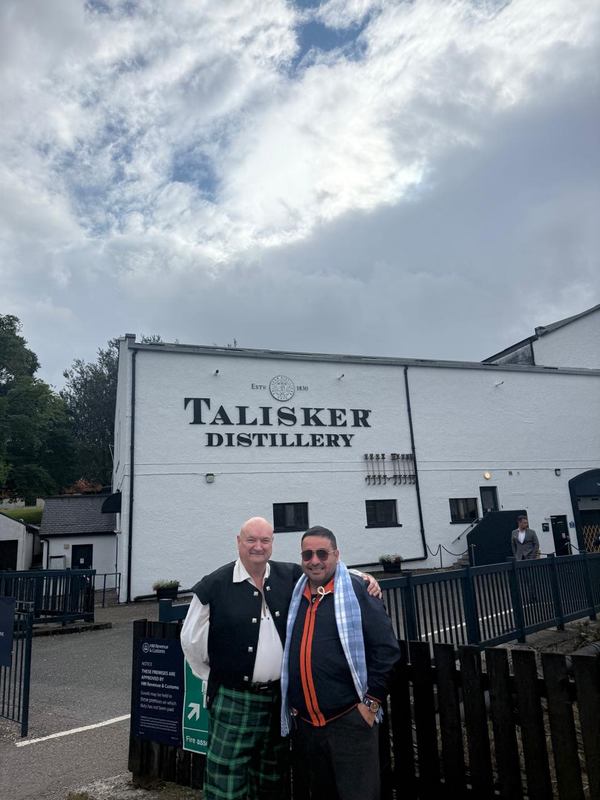 Tony in Highland dress with a guest outside Talisker Distillery on Skye